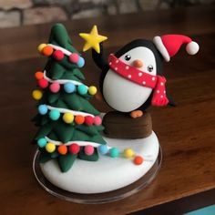 a small christmas tree with a penguin figurine next to it on a table