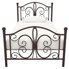 an iron bed frame with white sheets and decorative scroll designs on the headboard is shown