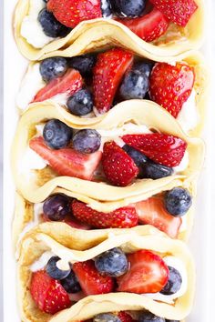 some fruit is on top of crepes with whip cream and strawberries in the middle