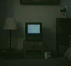 a small tv sitting on top of a table next to a lamp and a painting