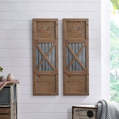 two wooden shutters are hanging on the wall next to an old trunk and box