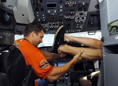 a man sitting in the cockpit of an airplane with his feet propped up on another person's leg