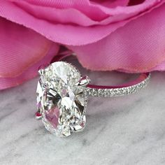 a close up of a diamond ring with a rose in the background