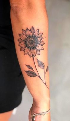 a woman's arm with a sunflower tattoo on it