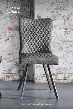 an upholstered chair sits in front of a brick wall with the words furniture village on it