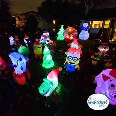 an assortment of inflatable christmas trees and animals are on the lawn at night