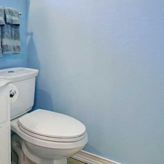 a white toilet sitting next to a sink in a bathroom under a blue painted wall