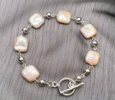 A very pretty bracelet made from square shaped pearls in delicate shades of pale peach or cream depending on the light.  Each pearl is naturally textured and contrasts beautifully with the smooth round sterling silver beads alternating between each pearl.  Finished with a sterling silver toggle clasp.  When making the bracelet, I had in mind occasions such as Mother's Day or weddings where this bracelet would be most appropriate but the choice is yours.  Wear it to lift a casual outfit, finish a Pale Peach, Pretty Bracelets, Short Necklace, Toggle Clasp, Silver Pearls, Sterling Silver Bead, Chain Link Bracelet, Matching Earrings, Silver Beads