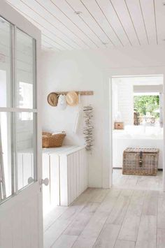 a kitchen with white walls and wood flooring next to an open door that leads to a bedroom