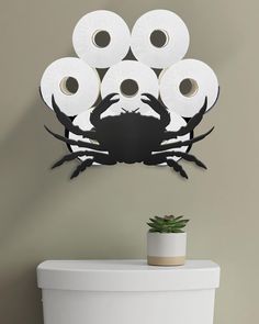 a toilet with several rolls of toilet paper in the shape of a crab on it