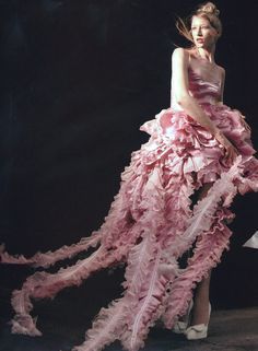 a woman in a pink dress with feathers on it