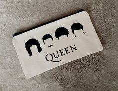 a zippered pouch with the words queen printed on it and four silhouettes of women's hair