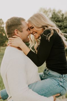 a man and woman embracing each other while sitting on a bench in front of trees