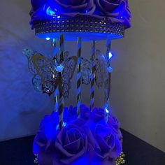 there is a purple cake with candles and roses on the top, surrounded by blue lights