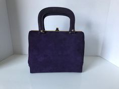 "This is an elegant 50s art deco, Kelly style structured handbag in deep purple suede and leather. It is a Kelly frame bag dating to the 50s. This beautiful handbag's interior features black faux leather interior with one zippered pocket and one slip pocket with gold piping. Kiss-lock closure. In excellent vintage condition considering age and use. Approximate measurements - 7\" high x 8 1/4\" wide and 4\" in depth. The strap drop is 3\". Marked Made in Canada. Prices are listed for Canada and U Vintage Purple Bags For Formal Occasions, Classic Purple Rectangular Satchel, Classic Purple Evening Bag, Purple Rectangular Satchel For Formal Occasions, Formal Purple Rectangular Satchel, Elegant Purple Rectangular Satchel, 50s Art, Structured Handbags, Purple Suede