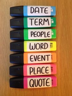 four markers with words written on them sitting next to each other in front of a wooden table