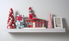 an elf is sitting on top of a shelf next to christmas decorations and gifts,