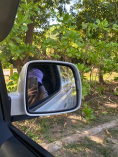 a person taking a photo in the side mirror of a car with their cell phone