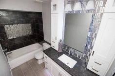 a bathroom with black and white tiles on the walls, toilet, sink and bathtub