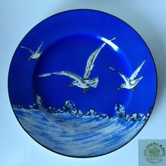 a blue plate with two white birds flying over the ocean on it's side