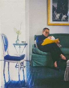 a man sitting on a green couch reading a book