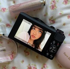 a camera and some perfume bottles on a bed