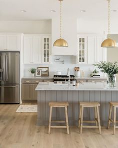 a kitchen with two stools in front of an island and stainless steel refrigerator freezer