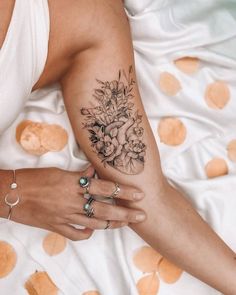 a woman laying on top of a bed covered in lots of dots with tattoos on her arm