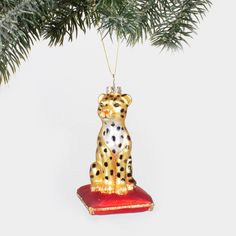 a christmas ornament shaped like a cheetah sitting on a red cushion