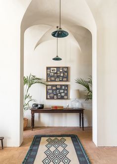 an archway leading into a living room with pictures on the wall and plants in vases