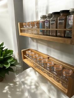 two wooden shelves filled with jars on top of a white counter next to a potted plant