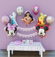 a table topped with lots of balloons and minnie mouse decorations