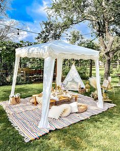 a white canopy bed sitting on top of a grass covered field