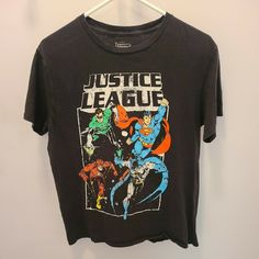 the justice league t - shirt is hanging on a hanger