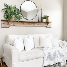 a living room with a white couch and mirror on the wall