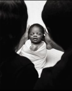 a black and white photo of a baby being held up to her mother's face