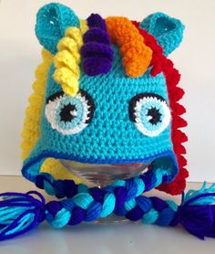 a crocheted blue hat with orange, yellow and red horns on it's head