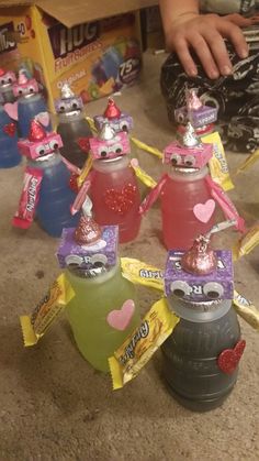 some kind of water bottle with candy on top and other items around it in the shape of people