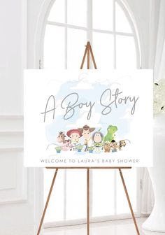 a baby story welcome sign on an easel in front of a window with white curtains