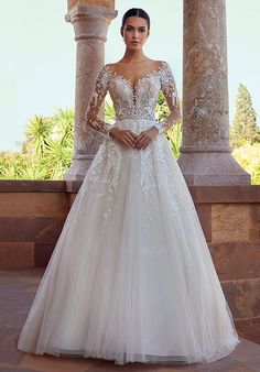 a woman in a wedding dress standing on a stone walkway with columns and pillars behind her