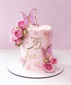 a pink birthday cake decorated with flowers and butterflies