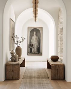 the hallway is decorated in white and has two vases on either side of it