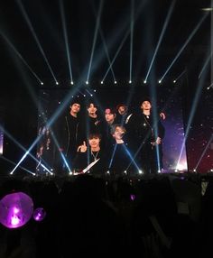 a group of young men standing on top of a stage under spotlights in front of a crowd