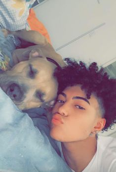 a woman laying in bed next to a dog