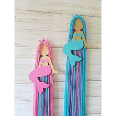 two paper cutouts of mermaids are hanging on the wall