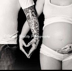 a man and woman holding hands with tattoos on their arms, while the pregnant girl holds her belly