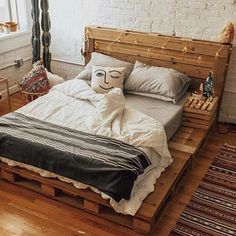 a bed made out of wooden pallets in a room with brick walls and wood floors