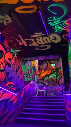 the stairs are lit up with neon lights and graffiti on them in this dark room