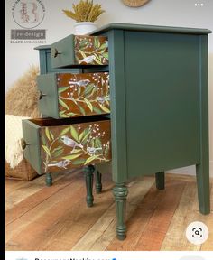 a green dresser with drawers painted with flowers and leaves on the front, sitting on a wooden floor next to a wall