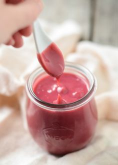 a person is dipping something into a jar